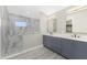 Double vanity bathroom with gray cabinets and marble shower at 35 Broadmoor Ln, Rotonda West, FL 33947