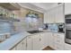 White kitchen with wood-look backsplash and stainless steel appliances at 5856 Gasparilla Rd # M27, Boca Grande, FL 33921