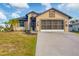 Tan house with dark brown garage door and landscaping at 6128 Catalan St, Englewood, FL 34224