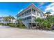 Two-story white condo with screened porch and stairs, surrounded by tropical landscaping at 7482 Palm Island Dr # 2511, Placida, FL 33946