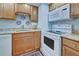 Kitchen features wood cabinets, granite counters, white appliances, and subway tile backsplash at 84 Boundary Blvd # 165, Rotonda West, FL 33947