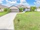 Front exterior of home with driveway and two-car garage, lush lawn at 171 Medalist Rd, Rotonda West, FL 33947