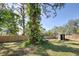 Large backyard with a wooden fence and mature trees at 1860 Bluebird Ln, Englewood, FL 34224