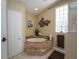 Elegant bathroom with a corner soaking tub, tiled step, and decorative wall art at 47 Sportsman Ln, Rotonda West, FL 33947