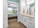 Bright bathroom with white vanity, light wood-look floors, and view of the bedroom at 7064 Baypine Ln, Englewood, FL 34224