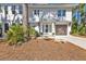 Charming two-story home with white siding, a wooden garage door, and lush landscaping at 7064 Baypine Ln, Englewood, FL 34224