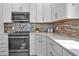 Modern kitchen boasting stainless steel appliances, white cabinets, and light countertops at 7064 Baypine Ln, Englewood, FL 34224