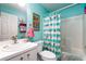 Bathroom with flamingo-themed shower curtain, teal walls, and white vanity at 9300 Miami Cir, Port Charlotte, FL 33981