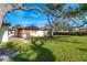 Backyard view of house showcasing green lawn and mature trees at 99 W Riverview Ave, Englewood, FL 34223