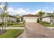 Brick paved driveway leads to a beige house with a white garage door and landscaped front yard at 2759 Lavandula Ct, North Port, FL 34289