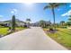 Long concrete driveway leads to a house with a metal roof and surrounded by green lawns and palm trees at 646 Boundary Blvd, Rotonda West, FL 33947