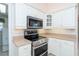 Kitchen with white cabinets, stainless steel appliances, and a view of the laundry room at 646 Boundary Blvd, Rotonda West, FL 33947