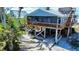 Elevated coastal home with a spacious wooden deck and tropical landscaping, perfect for relaxing outdoors at 9526 Jolly Roger Trl, Placida, FL 33946