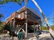 Exterior view of a elevated beach home featuring a wooden deck and stairs at 9526 Jolly Roger Trl, Placida, FL 33946