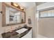 Well-lit bathroom features a black countertop, a large mirror, and a tiled shower at 1493 Janet Pl, Englewood, FL 34223