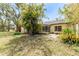 View of home's backyard with mature landscaping, screened in lanai and grassy lawn at 1828 Whispering Pines Cir, Englewood, FL 34223