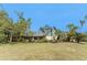 Exterior of home with green roof, yellow siding, mature trees and blue sky at 1828 Whispering Pines Cir, Englewood, FL 34223
