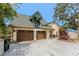 Home exterior with three-car garage, dormer, and brick paver driveway at 1828 Whispering Pines Cir, Englewood, FL 34223