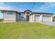 Gray house with three-car garage and manicured lawn at 195 W Pine Valley Ln, Rotonda West, FL 33947