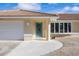 Tan house exterior with teal front door, attached garage, and landscaped walkway at 370 Capstan Dr, Placida, FL 33946