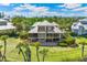 Aerial view of a home boasting screened porches, multiple levels, lush lawns, and tropical landscaping at 45 Seawatch Lake Dr, Boca Grande, FL 33921
