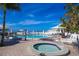 Inviting outdoor pool and spa area with lounge seating, umbrellas, and lush tropical landscaping against a beautiful sky at 5000 Gasparilla Rd # 73A, Boca Grande, FL 33921