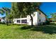 Condo's back exterior, showcasing a grassy yard and lush tree at 502 Pine Hollow Cir # 502, Englewood, FL 34223