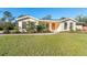 Cute ranch home with orange door, landscaped lawn, and solar panels at 5868 Denison Dr, Venice, FL 34293