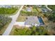 Aerial view of a home with a screened-in pool, a large driveway, and mature landscaping at 7330 Printer St, Port Charlotte, FL 33981