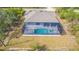 Aerial view of a home with a screened-in pool, mature landscaping, and a well-manicured lawn at 7330 Printer St, Port Charlotte, FL 33981