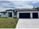 Stunning modern home featuring a two-car garage, lush lawn and a stylish front entrance with a beautiful blue sky at 7330 Printer St, Port Charlotte, FL 33981