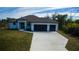 Beautiful modern home featuring a two-car garage, lush lawn and a stylish front entrance with a beautiful blue sky at 7330 Printer St, Port Charlotte, FL 33981