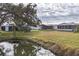 Scenic backyard view featuring a tranquil pond surrounded by lush greenery at 735 Summersea Ct, Englewood, FL 34223