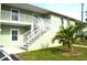Light green condo building with white stairs and railings, landscaping, and parking at 8100 Memory Ln # 207, Rotonda West, FL 33947