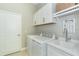 Bright and spacious laundry room with white cabinets and a utility sink at 10958 Trevino St, Englewood, FL 34223