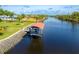 Aerial view of a private boat dock with a covered lift on a tranquil waterway surrounded by lush greenery and neighborhood homes at 13307 Eisenhower Dr, Port Charlotte, FL 33953