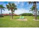 Expansive backyard featuring lush green grass, mature palm trees, and a charming seating area for outdoor enjoyment at 13307 Eisenhower Dr, Port Charlotte, FL 33953
