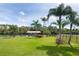 Manicured lawn in the backyard with a boat dock and lift on the canal with mature palm trees and blue skies at 13307 Eisenhower Dr, Port Charlotte, FL 33953