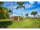 Lush backyard featuring mature palm trees, a decorative lighthouse, and a well-manicured lawn with ample space for outdoor activities at 13307 Eisenhower Dr, Port Charlotte, FL 33953