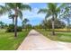 Long driveway lined with palm trees, leading to a secluded home with beautiful landscaping at 13307 Eisenhower Dr, Port Charlotte, FL 33953