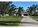 Single-story home exterior with a long driveway, lush landscaping, and palm trees at 13307 Eisenhower Dr, Port Charlotte, FL 33953