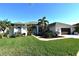 Single-story home exterior, featuring a light-colored facade, lush landscaping, and a two-car garage at 13307 Eisenhower Dr, Port Charlotte, FL 33953