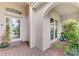Inviting entryway with red brick pavers, white framed front door and French doors, and lush landscaping at 13376 Creekside Ln, Port Charlotte, FL 33953