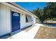 Charming single-story home featuring a blue front door, a well-maintained lawn, and a clear blue sky at 7330 Regina Dr, Englewood, FL 34224