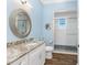 This bright blue bathroom features a light vanity, and a walk-in shower at 9240 Pine Cove Dr, Englewood, FL 34224