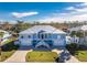 Beautiful two-story blue home with a white metal roof, dual garages, and a well-manicured front yard with lovely landscaping at 9240 Pine Cove Dr, Englewood, FL 34224