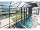 Enclosed in-ground pool and spa are viewed from above; the enclosure provides beautiful waterfront views at 9240 Pine Cove Dr, Englewood, FL 34224
