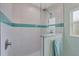 Modern shower featuring large white tiles with an accent stripe of blue tile and glass partition at 11247 Euler Ave, Englewood, FL 34224