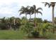 A tranquil backyard with lush greenery, decorative palm trees, and outdoor seating areas at 170 Antilla Dr, Rotonda West, FL 33947