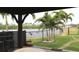 A backyard with view of the water, lush palm trees and a covered seating area for relaxation at 170 Antilla Dr, Rotonda West, FL 33947